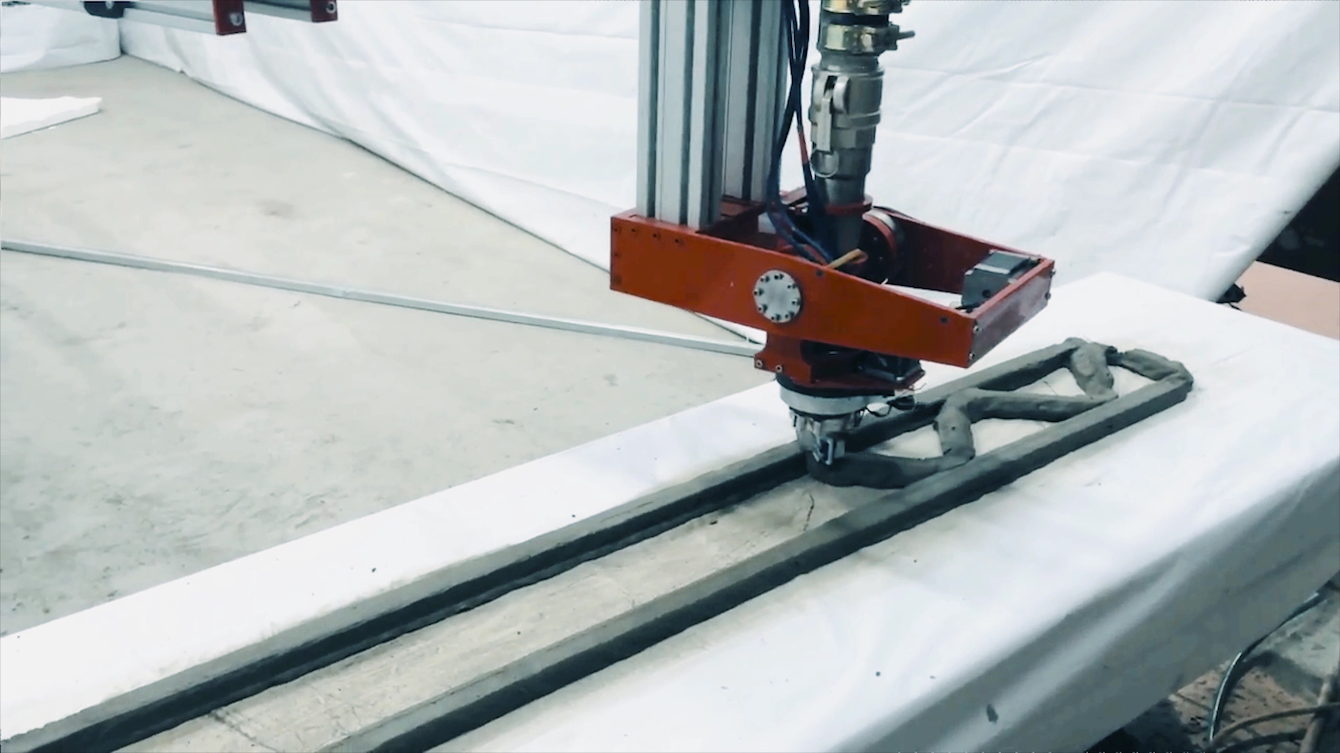 Boquilla de una impresora 3D depositando material cementicio por capas para formar un elemento de pared